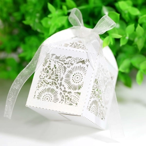 Détail de découpe laser motif floral sur boîte à bonbons blanche et ruban argenté scintillant