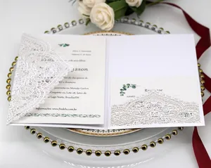 Elegant white laser-cut lace wedding invitation set with floral decor on a golden tray