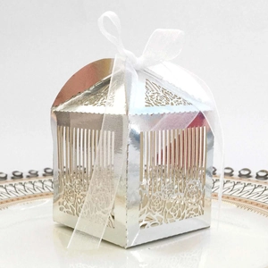 Detail of silver laser-cut wedding favor box with floral patterns and white organza ribbon
