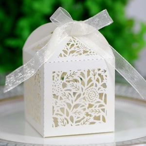 Close-up of white laser-cut floral candy box with elegant organza ribbon on a plate