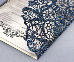 Close-up of laser-cut navy blue glitter invitation with intricate floral patterns