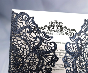 Detailed close-up of dark blue glitter laser-cut floral wedding invitation card