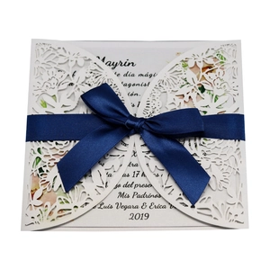 White laser cut wedding invitation with navy blue ribbon bow and floral butterfly pattern