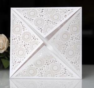 Detail showing white laser cut invitation card with floral patterns and pearl finish