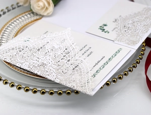 Detailed macro of laser-cut lace wedding invitation with white floral hollow patterns