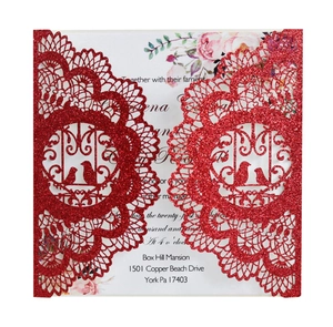 Close-up of glittery pink laser-cut invitation with intricate lace and bird design