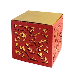 Close-up of laser-cut red and gold wedding candy box with intricate scroll patterns