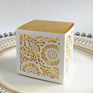 Macro view of laser-cut floral pattern with gold lining on white gift box