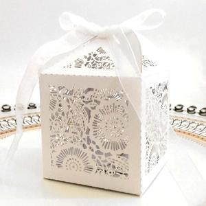 Détail d'une boîte cadeau blanche découpée au laser avec motifs floraux et ruban