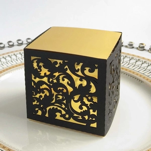 Macro detail of laser-cut black and gold gift box with intricate filigree patterns