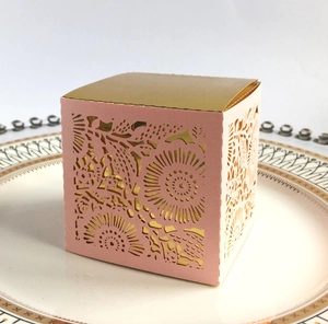 Detail of pink laser-cut wedding favor box with floral patterns and a gold mirror lid