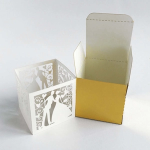 Detail of laser-cut wedding favor box with bride and groom silhouette and gold inner box