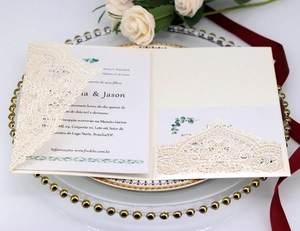 Elegant ivory laser-cut lace wedding invitation set on a white tray with roses