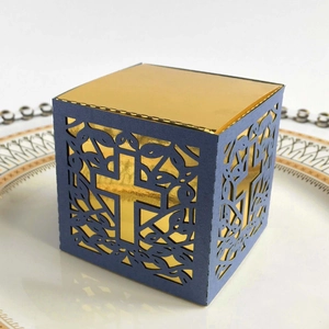 Detail of laser-cut cross pattern on blue gift box with gold liner on white plate