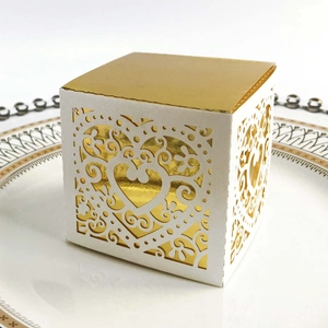 Detail of white laser-cut gift box with golden heart patterns and vine hollow design