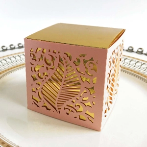 Detailed laser-cut vine patterns on a pink and gold gift box for wedding favors