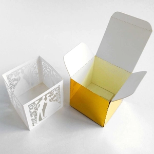 Detail of laser-cut wedding favor box featuring heart patterns and gold inner box