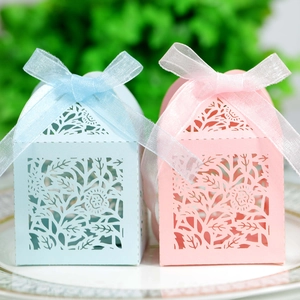 Macro shot of laser-cut rose candy boxes in pink and blue with organza ribbon