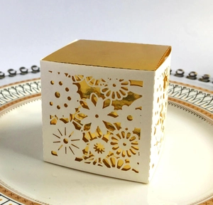 Detail of laser-cut floral patterns on white and gold wedding candy gift boxes
