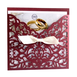 Laser cut wine red wedding invitation with floral patterns and a white cream bow