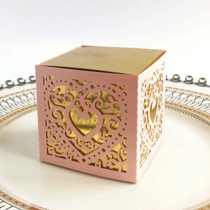 Detail of pink laser-cut candy box with intricate heart patterns and gold inner lining
