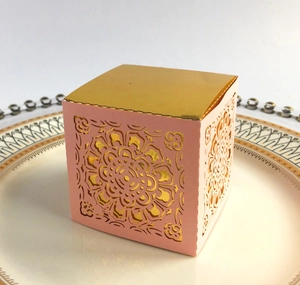 Dettaglio macro della scatola regalo rosa con coperchio dorato e intagli floreali