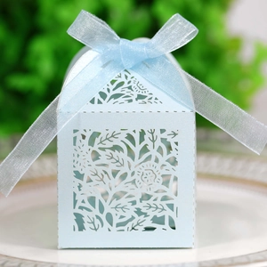 Close-up of laser-cut hollow rose patterns on a light blue wedding favor gift box with ribbon