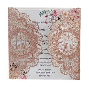 Macro detail of rose gold laser-cut lace wedding invitation with pink floral inner card