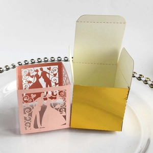 Close-up of pink laser-cut wedding favor box with bride and groom silhouette detail