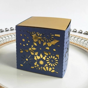 Detail showing laser-cut purple gift box with intricate floral hollow design and gold lining