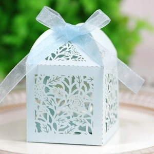 Macro shot of light blue laser-cut rose hollow candy box with organza ribbon on white plate