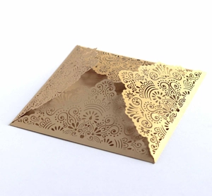 Macro detail of laser-cut gold wedding invitation with intricate floral lace pattern