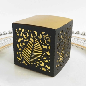 Close-up of laser-cut hollow leaf pattern on black and gold wedding favor candy box