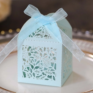 Detailed laser-cut light blue wedding favors box with matching ribbon on a white plate