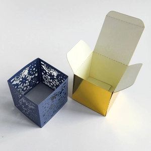 Detailed laser-cut floral pattern on navy box alongside a glossy gold mirror gift box