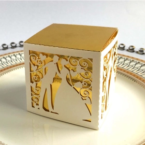 Detail of laser-cut wedding favor box featuring bride and groom silhouette and gold liner