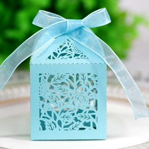 Close-up of laser-cut light blue wedding favor box with floral patterns and a silk ribbon