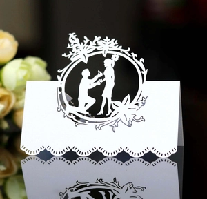 Elegant white laser-cut wedding place cards with a romantic couple silhouette and floral ring
