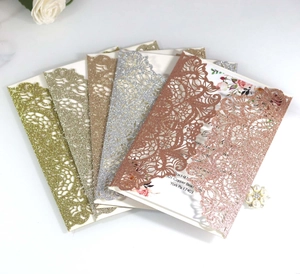 Close-up of laser cut glitter invitation covers with floral printed inner cards