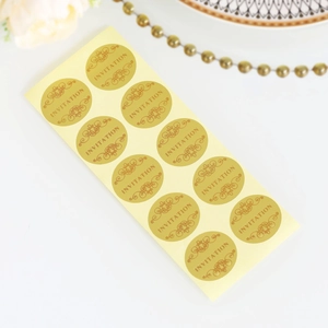Macro shot of 12 circular gold invitation stickers with elegant engraving on cream paper