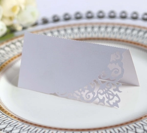 Macro view of laser-cut floral patterns on white and purple folded wedding place cards