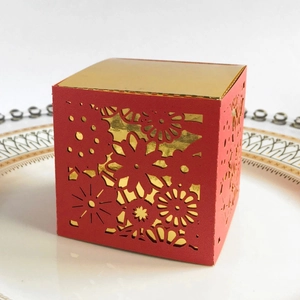 Detail view of red laser-cut gift box with floral patterns on a white porcelain plate