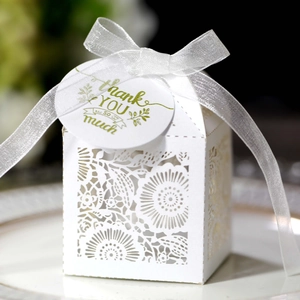 Détail de boîte à dragées blanche découpée au laser avec motifs floraux et étiquette