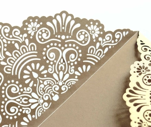 Macro detail of laser-cut wedding invitation pocket with intricate floral hollow pattern