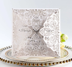 Elegant laser-cut wedding invitation with intricate floral hollow design on white paper