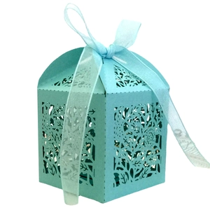 Macro shot of light blue laser cut favor box with floral patterns and a satin ribbon bow