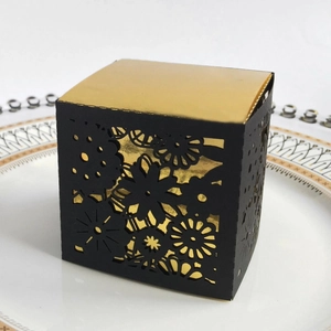 Detail of square black laser-cut gift box with floral patterns and gold interior