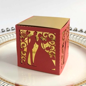 Detail of red laser-cut wedding favor box with bride and groom silhouette on white plate