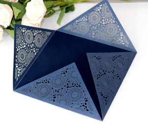 Detailed close-up of navy blue laser-cut wedding invitation with mandala lace pattern