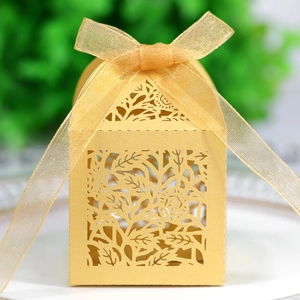 Macro shot of gold laser-cut rose wedding favor box with an organza ribbon bow